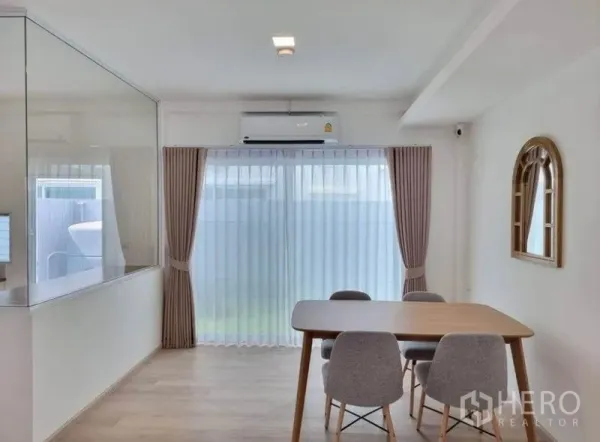 联排别墅 出租在Prawet, Bangkok - 采光充足的用餐区，玻璃隔断、纱帘、空调及通向花园的推拉门。