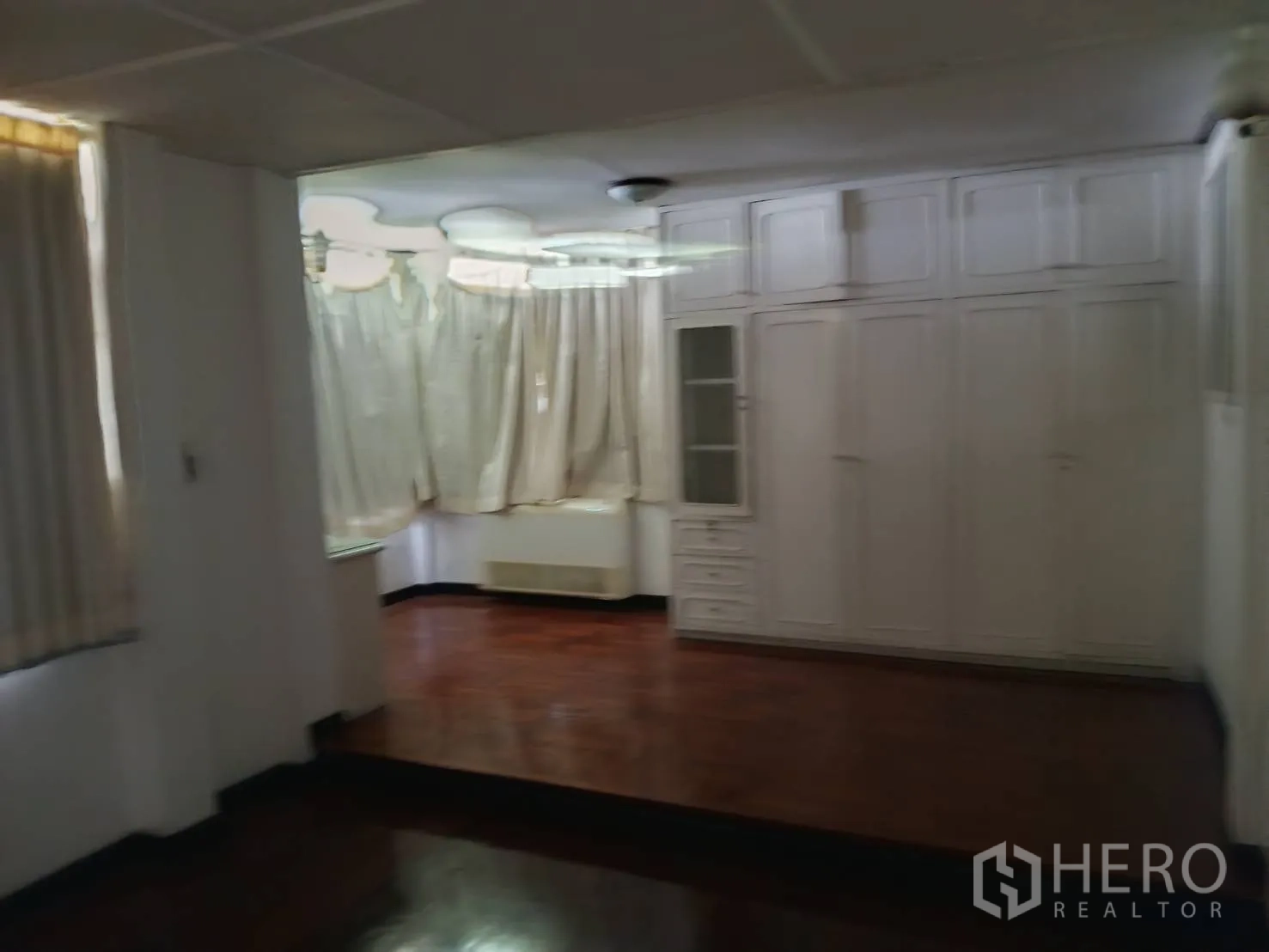 Detached House for sale in Watthana, Bangkok - Spacious room with built-in white wardrobes and polished wood floors.
