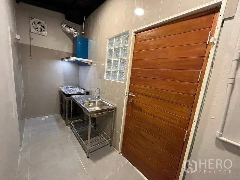 联排别墅 for rent in Phra Khanong, Bangkok - 紧凑厨房，带不锈钢水槽、抽油烟机与瓷砖墙面。