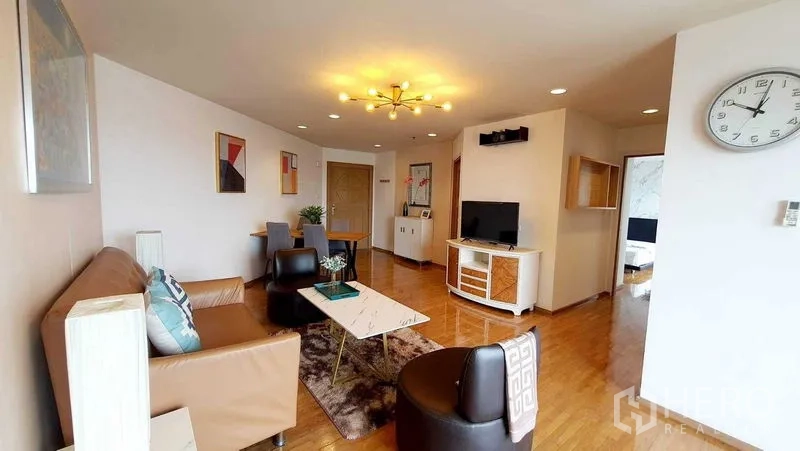 Condominium for sale in Bang Kho Laem, Bangkok - Open-plan living and dining room with sofa set, TV and warm wood flooring.