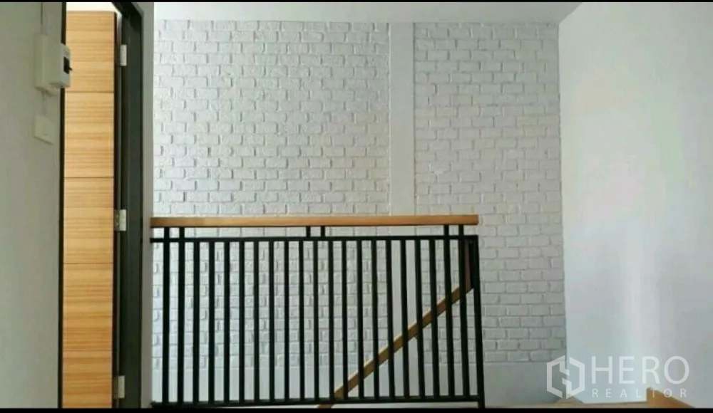 สำนักงานที่บ้าน ให้เช่าในLat Phrao, Bangkok - โถงชั้นบนพร้อมราวเหล็กสีดำและผนังอิฐทาสีขาวเป็นจุดเด่น