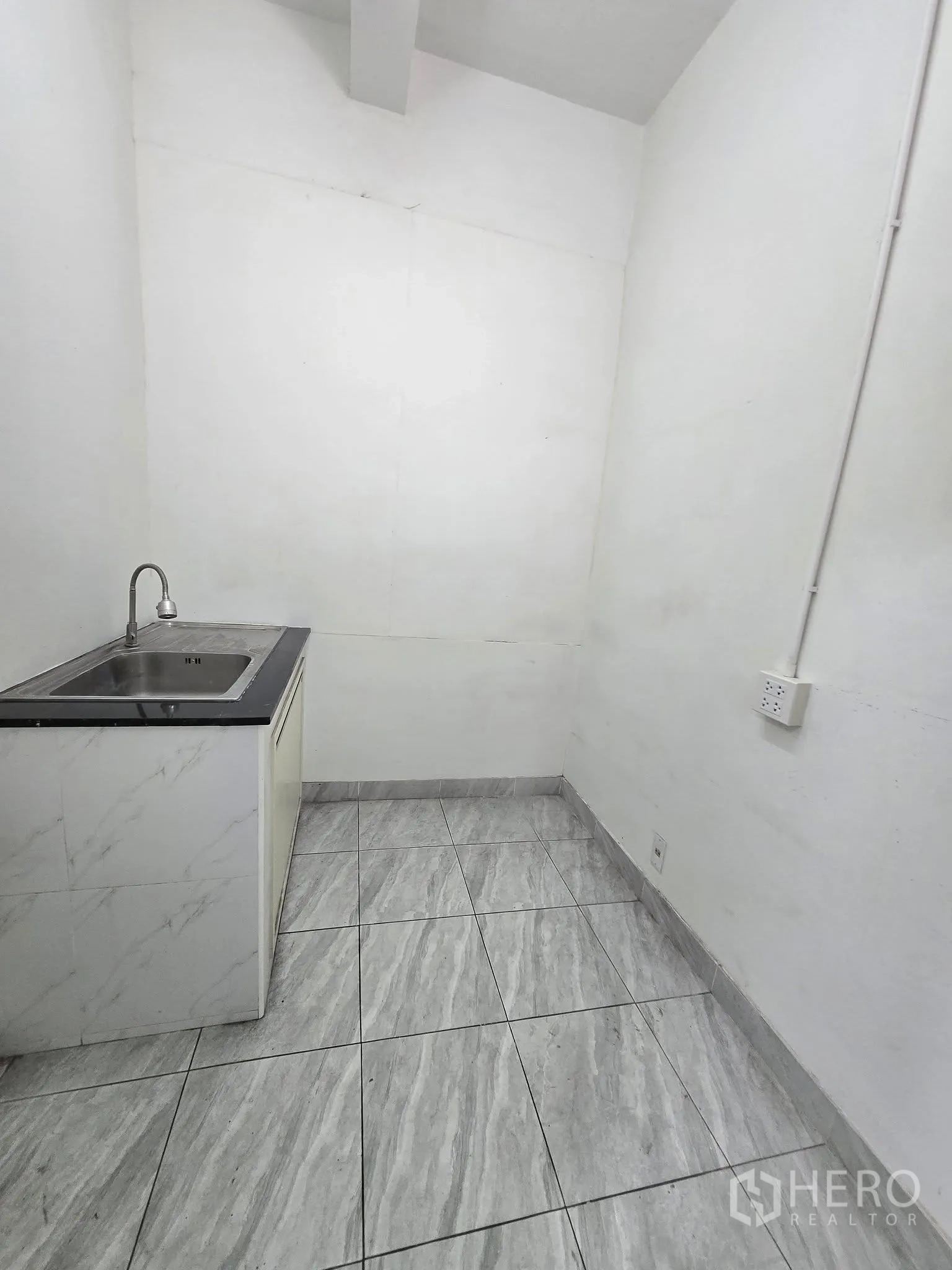 Office Space for rent in Khlong Toei, Bangkok - Compact pantry with a sink, countertop, and gray floor tiles against white walls.
