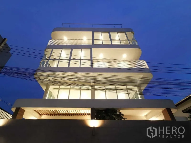 Home Office for sale in Suan Luang, Bangkok - Night view of contemporary multi-level facade with rounded balconies.