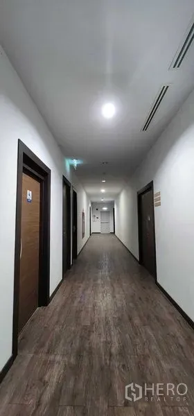 办公空间 出租在Khlong San, Bangkok - 曼谷 Khlong San 现代办公楼内，灯光明亮的木地板走廊与多扇门。