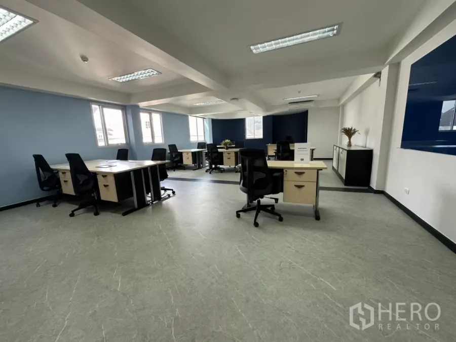 Office Space for rent in Watthana, Bangkok - Open-plan 66 sqm office with multiple workstations, blue accent walls, windows and bright fluorescent lighting.