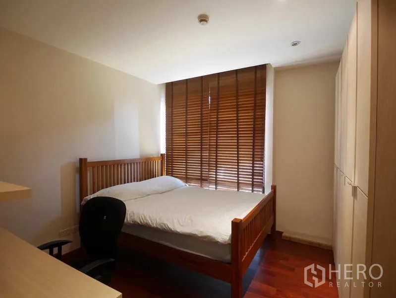 คอนโด ให้เช่าในPathum Wan, Bangkok - ห้องนอนอบอุ่น เตียงไม้ ตู้เสื้อผ้า และมู่ลี่หน้าต่าง