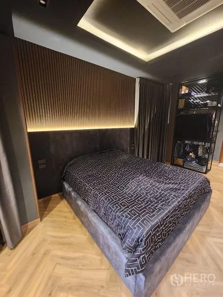 Detached House for sale in Thawi Watthana, Bangkok - Warm bedroom with accent lighting, textured headboard and herringbone floor.
