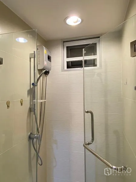 Condominium for rent - Glass-enclosed shower with water heater and small window for airflow.