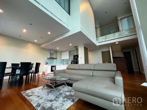 คอนโด ให้เช่าในKhlong Toei, Bangkok - อีกมุมของห้องนั่งเล่นเพดานสูงมีโซฟา ผืนพรม โต๊ะทานข้าว และครัว