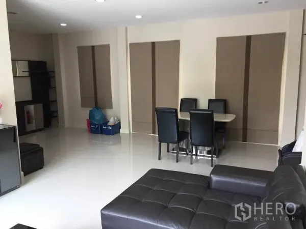 Detached House for rent or sale in Saphan Sung, Bangkok - Spacious open-plan living and dining area with leather sectional sofa, six-seat table and glossy tile floors.