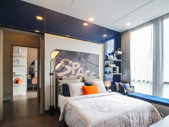 Detached House for rent or sale in Prawet, Bangkok - Stylish bedroom with blue accent wall, shelving and big windows.