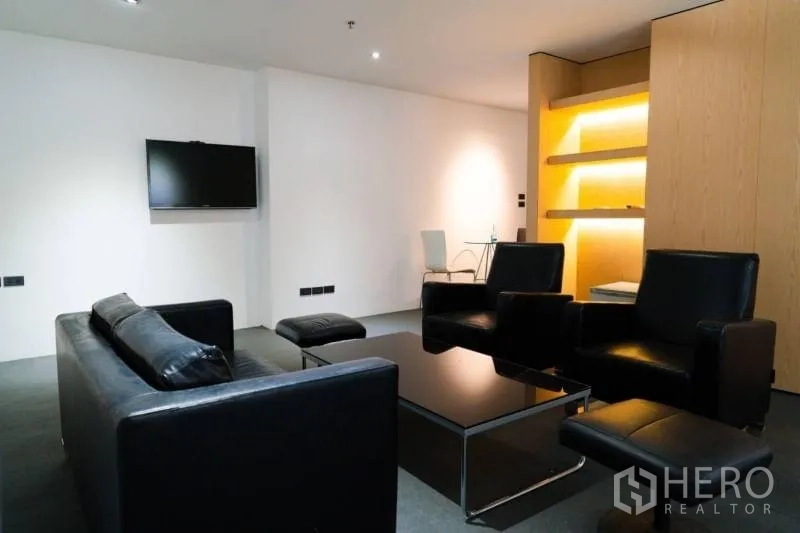 办公空间 出租在Khlong Toei, Bangkok - 客户休息区，黑色皮沙发、电视与背光置物架。