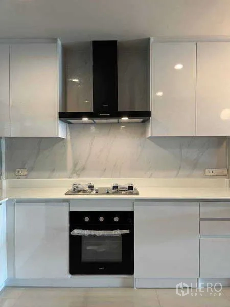 ทาวน์เฮาส์ ให้เช่าในKhlong Toei, Bangkok - ภาพระยะใกล้ของชุดครัวสีขาว เตาแก๊ส เตาอบ และเครื่องดูดควัน