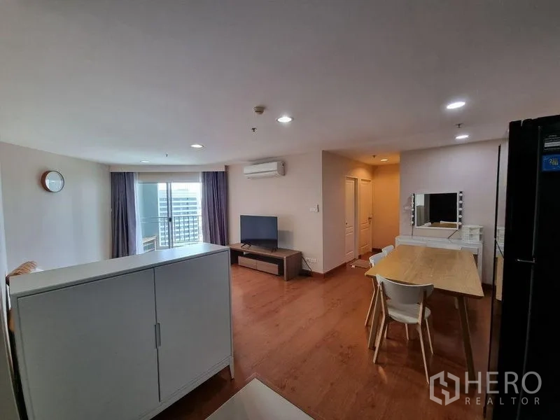 公寓 出租在Huai Khwang, Bangkok - 客厅带阳台推拉门、电视柜与窗帘，高层公寓景观。