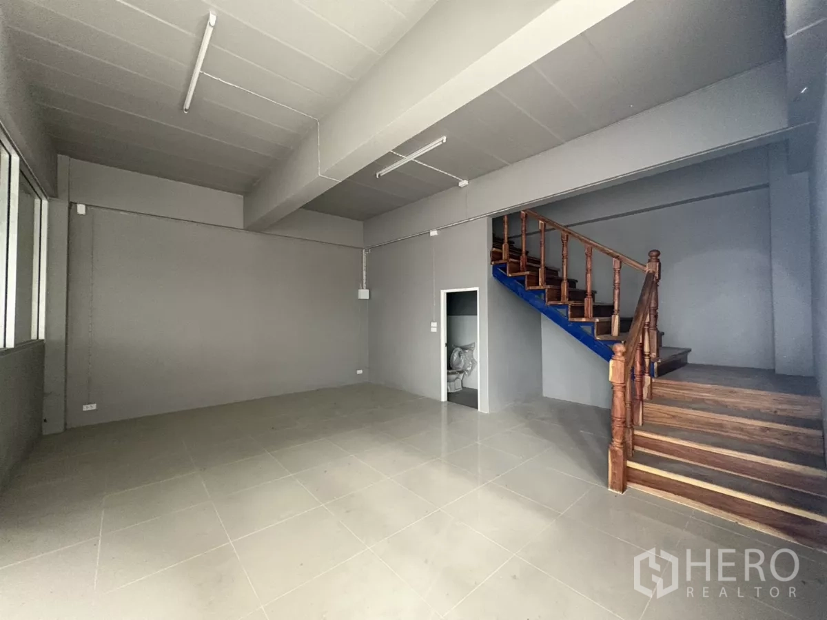 Warehouse for rent in Mueang Samut Prakan, Samut Prakan - Office area with wooden staircase and a door to the restroom beneath the stairs.