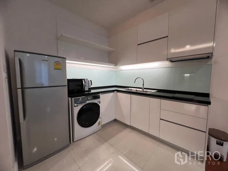 公寓 出租在Khlong Toei, Bangkok - L形厨房配冰箱、洗烘一体机、微波炉与橱柜照明。