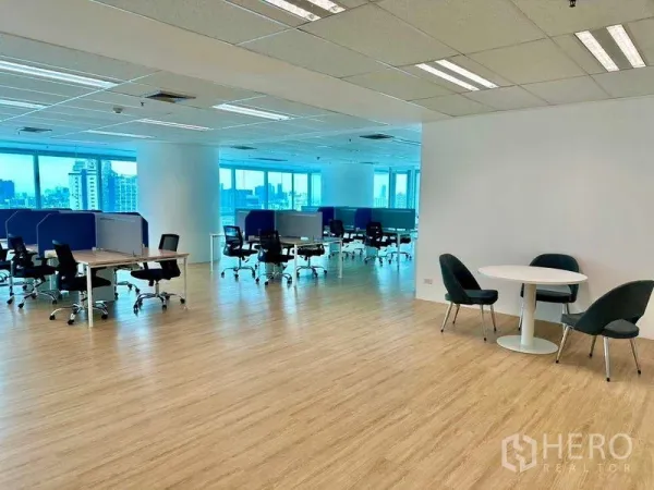 Office Space for rent - Spacious office floor with multiple desks, a round breakout table, and city views through large windows.