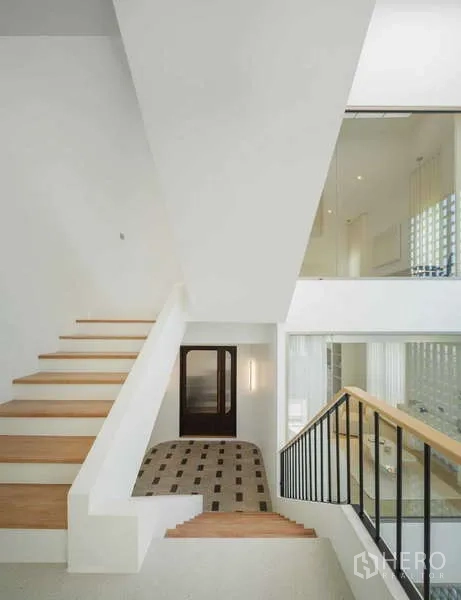 Home Office for sale in Chatuchak, Bangkok - Bright stairwell with white walls, wood‑tread stairs and black metal railing in a double‑height space.
