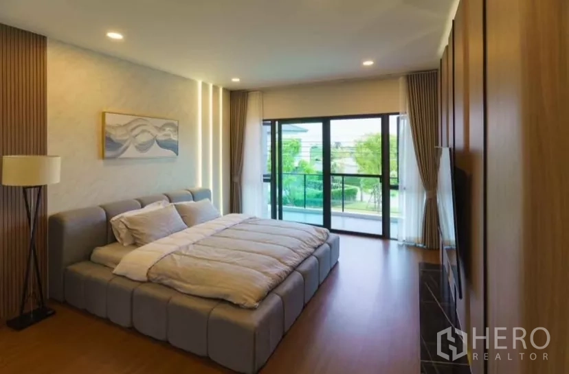 Detached House for rent or sale in Bang Phli, Samut Prakan - Master bedroom with king bed opening to a balcony and green community views.
