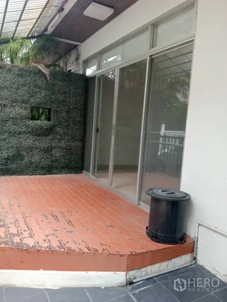 สำนักงานที่บ้าน ให้เช่าในKhlong Toei, Bangkok - เฉลียงหน้าบ้าน พื้นไม้ยกสเต็ป ผนังตกแต่งต้นไม้เทียม และประตูกระจกเลื่อน