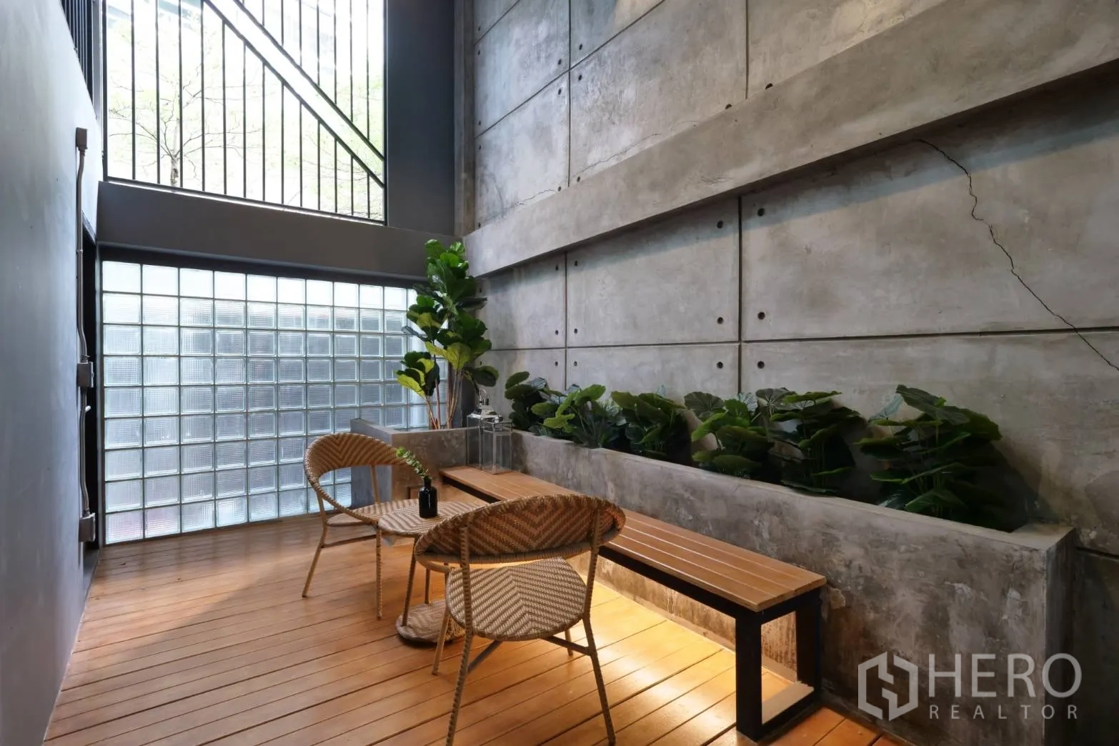 Townhouse for rent in Khlong Toei, Bangkok - Bright patio with glass-block wall, planter bed and rattan chairs.