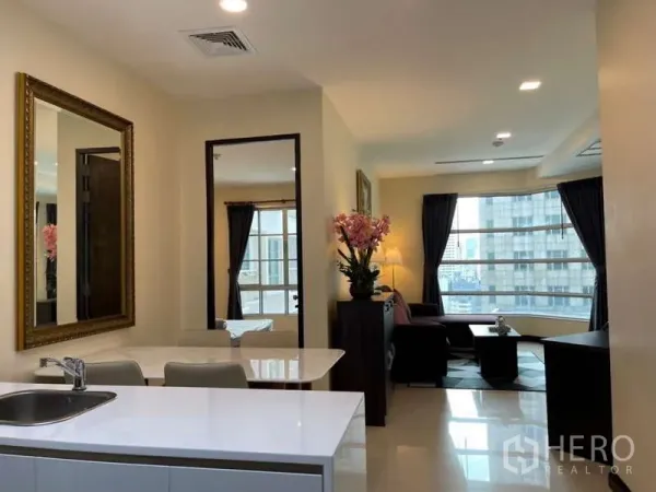 Apartment for rent in Khlong Toei, Bangkok - Another view of the open-plan living area with kitchen island and city-facing windows.