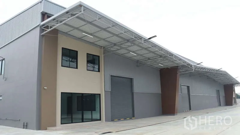 Warehouse for rent in Sam Phran, Nakhon Pathom - Contemporary warehouse exterior with attached office, large roller door and a wide covered loading canopy.