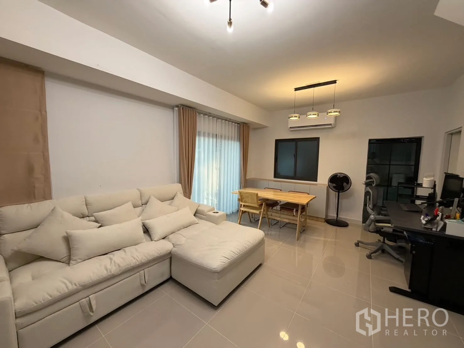 Townhouse for rent in Bang Phli, Samut Prakan - Living space with sofa, dining table and work desk beside a sliding glass door and window.