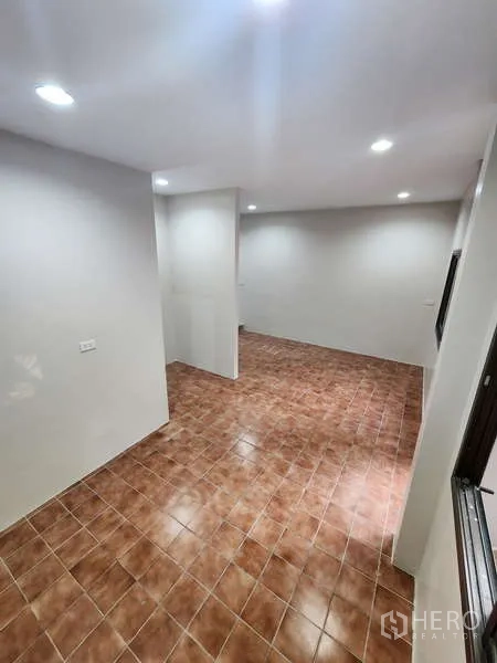 Townhouse for rent in Wang Thonglang, Bangkok - Long multi-purpose room with brown tiles and white walls.
