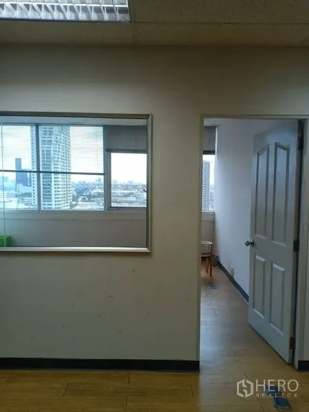 Office Space for rent - Bright office interior with partition window, open doorway, city view windows, wood floors and drop ceiling lights.