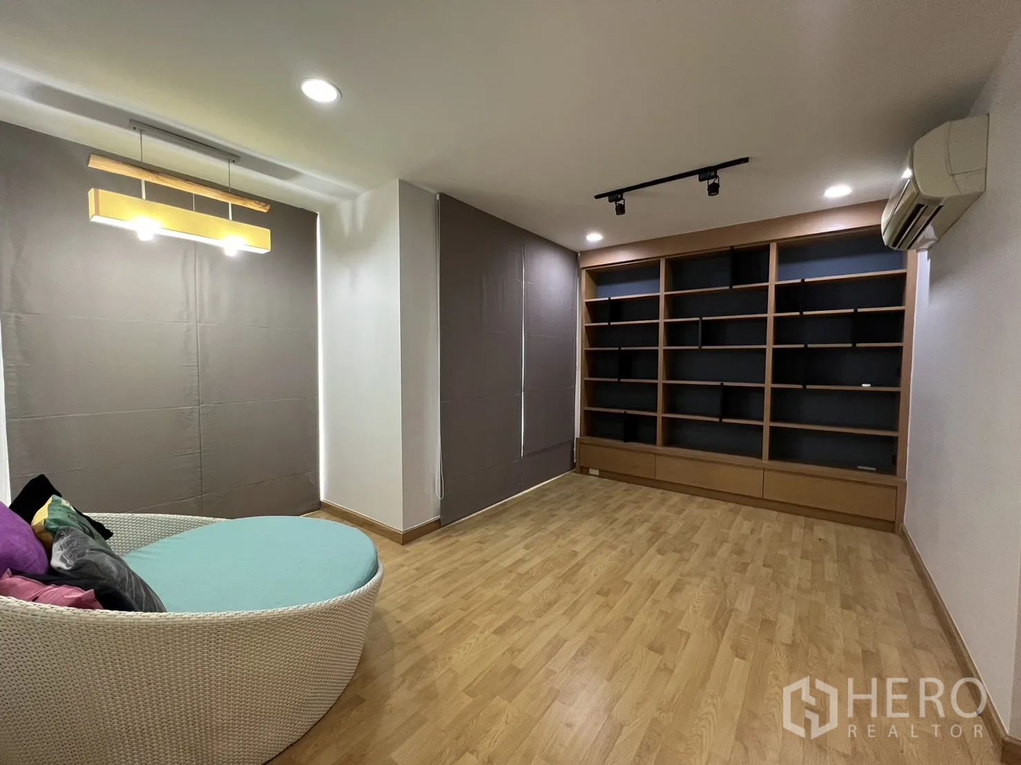 Townhouse for rent in Wang Thonglang, Bangkok - Cozy family room with shelving, air-conditioner and wooden floors.