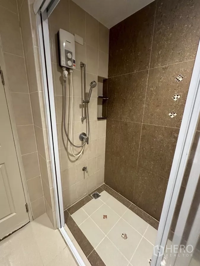 Townhouse for rent in Chom Thong, Bangkok - Close-up of tiled shower area with water heater and handheld spray.