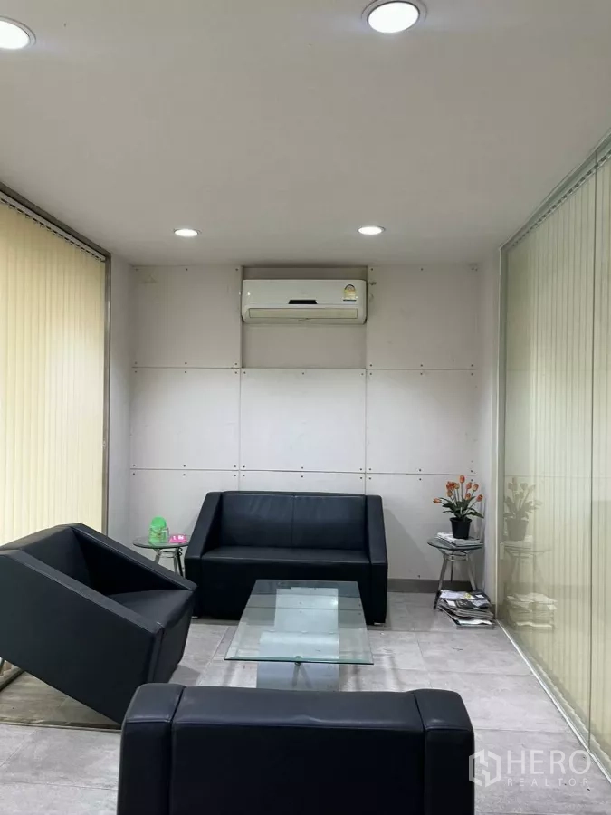 Home Office for rent in Khlong Toei, Bangkok - Private lounge with black leather sofas and a glass coffee table between tall blinds.