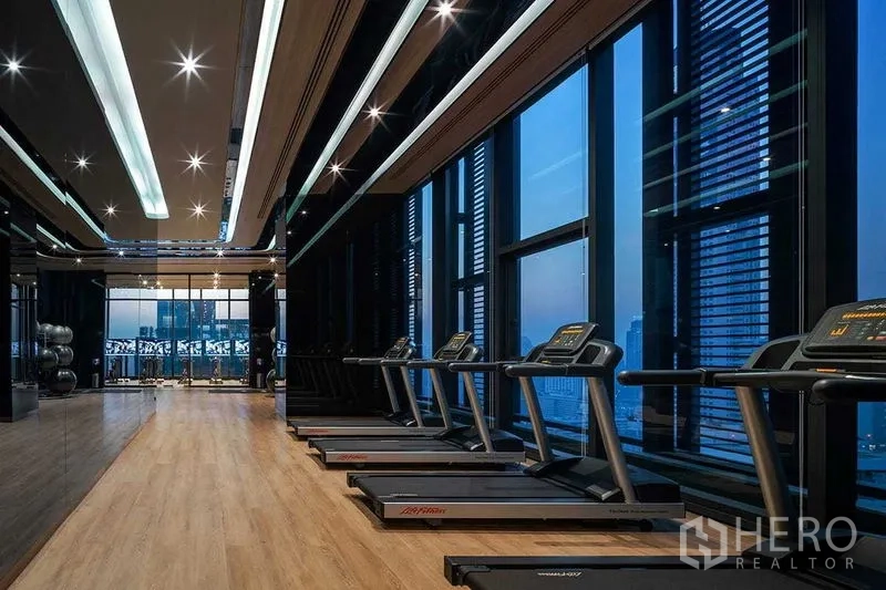 公寓 出租在Ratchathewi, Bangkok - 现代健身房，跑步机与落地窗，可望曼谷风景。