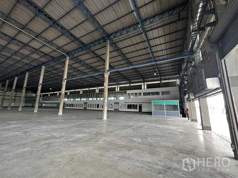 Factory for rent in Bang Sao Thong, Samut Prakan - Interior view toward mezzanine offices and multiple roller shutter entrances.