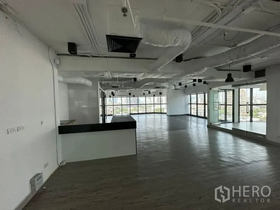 Office Space for rent - Large open office with pantry counter, exposed ceiling, and wraparound windows.