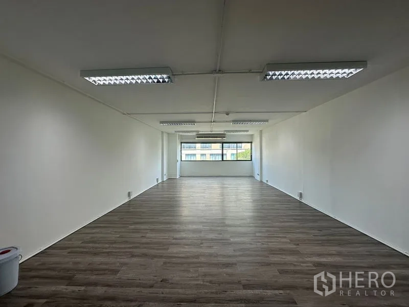 办公空间 出租在Bangkok - 空置办公室，白墙、顶灯，整面窗户可眺望周边建筑。