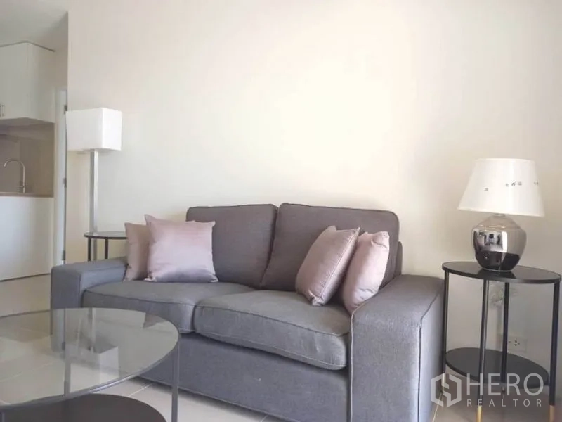 公寓 出租在Khlong Toei, Bangkok - 客厅灰色沙发搭配柔和抱枕，旁设边几与落地灯，温馨舒适。