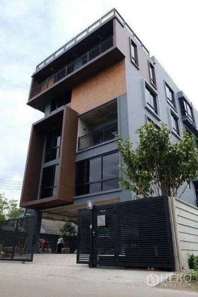 Office Space for rent or sale in Lak Si, Bangkok - Modern low-rise office building facade with gated entrance and geometric design.