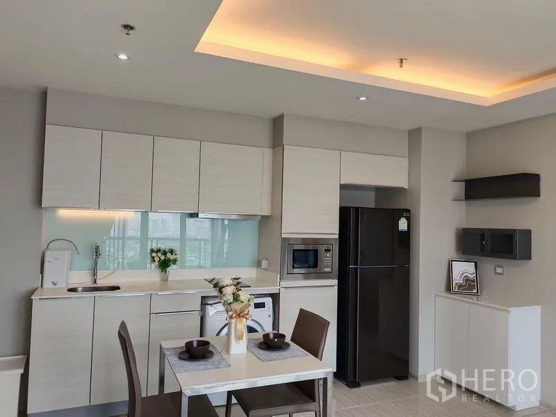 คอนโด ให้เช่าในWatthana, Bangkok - ครัวโทนอ่อนพร้อมตู้เก็บของ ตู้เย็น ไมโครเวฟ และโต๊ะทานอาหารสองที่นั่ง