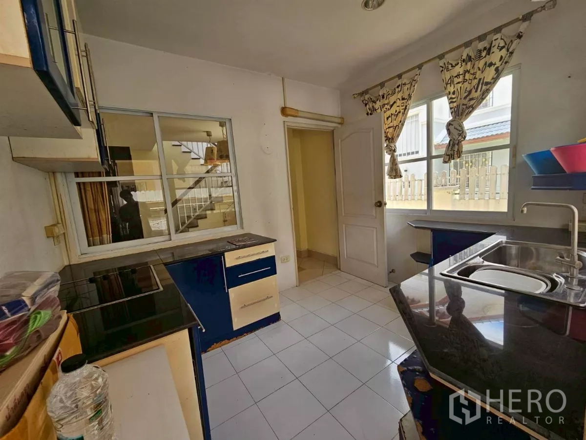 Detached House for rent or sale in Bang Lamung, Chon Buri - Kitchen alternate view with cooktop, cabinets, and an exterior door.