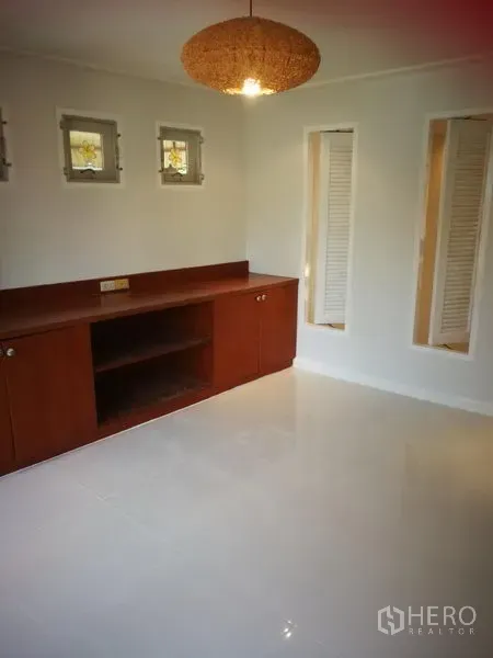Townhouse for rent or sale in Watthana, Bangkok - Bedroom or study with built-in wooden cabinet, small windows and white tile floor.