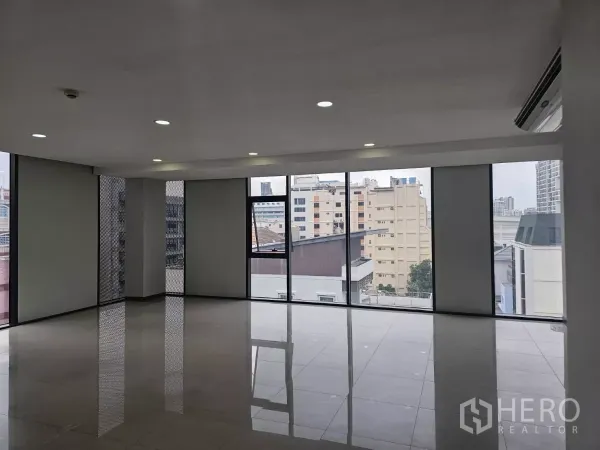 Office Space for rent in Sathon, Bangkok - Spacious office area with large windows and city views, reflective tiled flooring, and clean white walls.