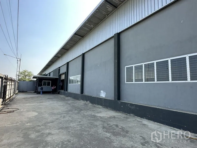工厂 出租在Lam Luk Ka, Pathum Thani - 长立面多窗设计，宽混凝土硬化场地便于卡车出入。