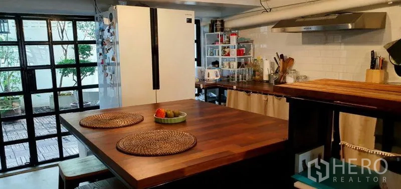 ทาวน์เฮาส์ ให้เช่าในKhlong Toei, Bangkok - ไอส์แลนด์ครัวท็อปไม้พร้อมสตูล มองออกสู่ลานผ่านหน้าต่างกรอบดำ