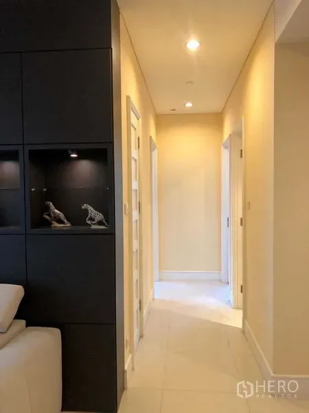 คอนโด ให้เช่า - โถงทางเดินไฟดาวน์ไลท์ข้างตู้โชว์สีดำ มุ่งสู่ห้องนอน