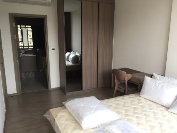 Condominium for rent in Watthana, Bangkok - Bright bedroom with built-in wardrobe, study desk, and ensuite bathroom access.