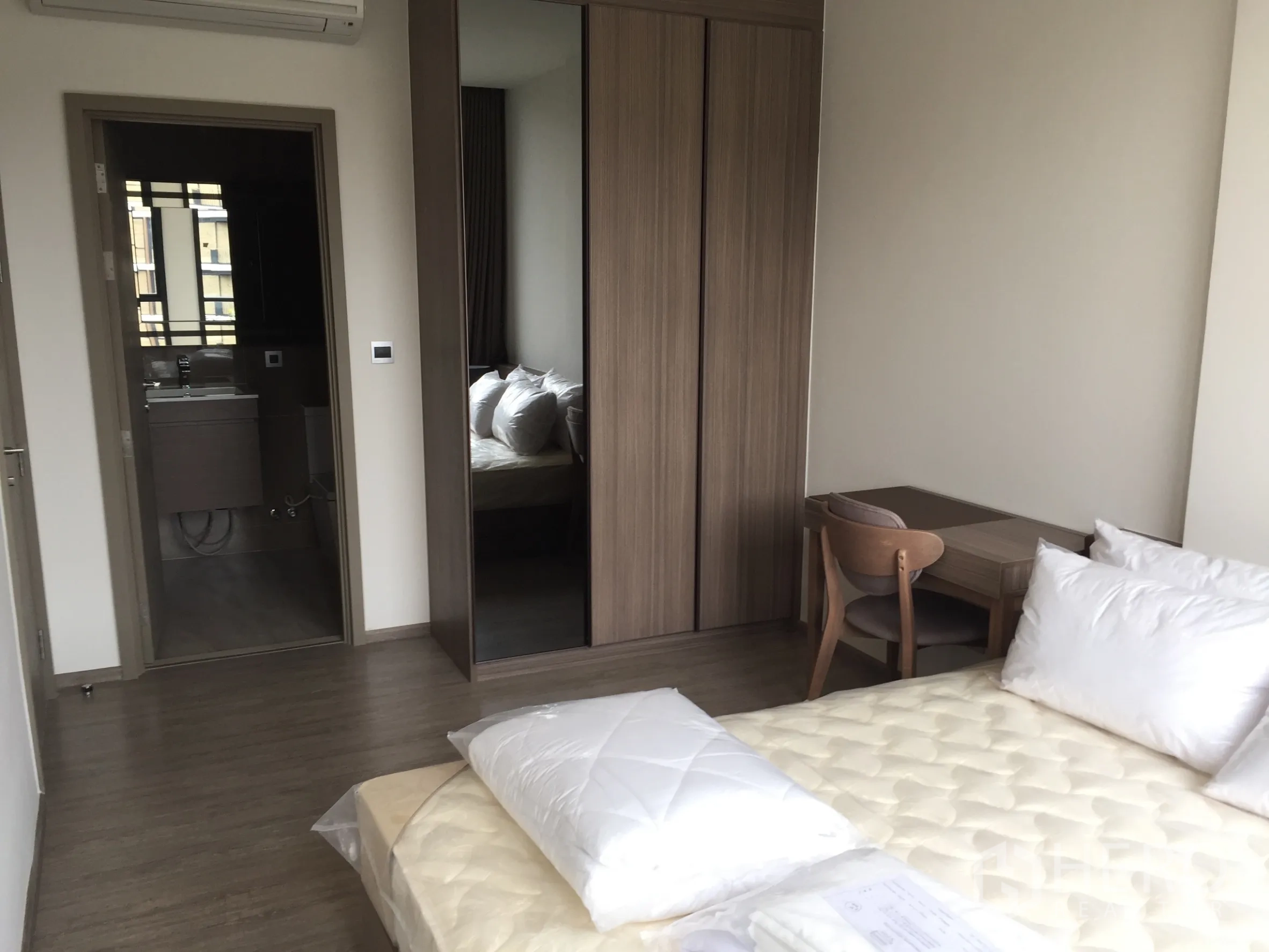 Condominium for rent in Watthana, Bangkok - Bright bedroom with built-in wardrobe, study desk, and ensuite bathroom access.