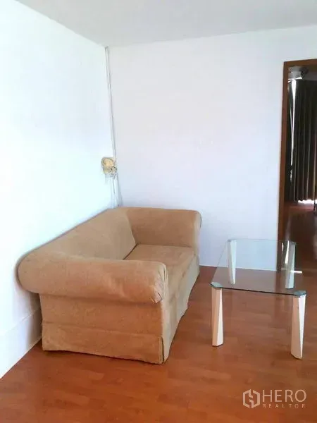 คอนโด ให้เช่าในWatthana, Bangkok - มุมนั่งเล่นกะทัดรัด โซฟาผ้าสีเบจและโต๊ะกลางกระจกบนพื้นไม้โทนอุ่น.