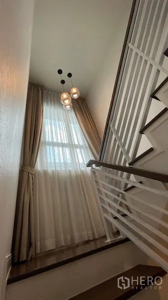 บ้าน ให้เช่าในBang Kapi, Bangkok - โถงบันไดหน้าต่างสูง ผ้าม่านโปร่ง โคมไฟแขวน ราวกันตกสีขาว